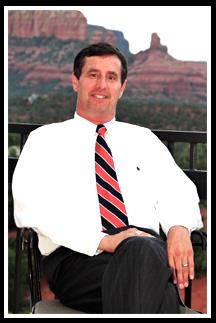 A man in a white shirt and tie sitting on a chair.